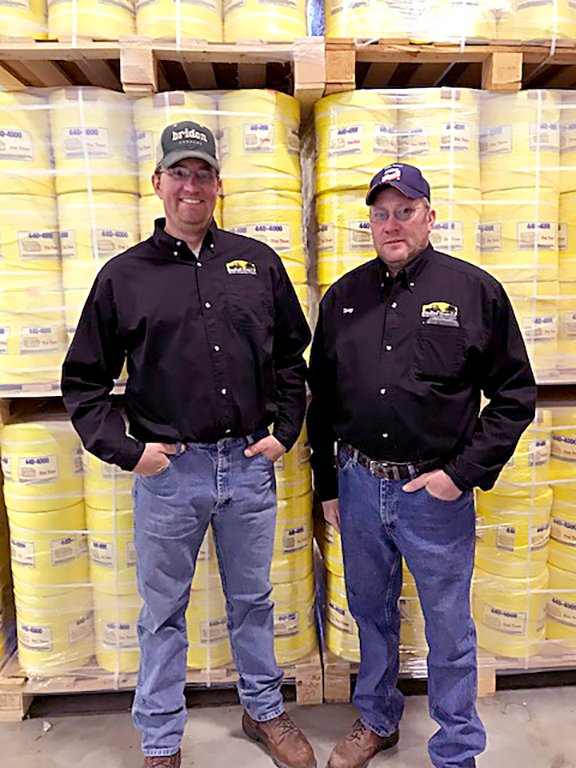 Tony and Rick Kellen, farmer-owners of The Fine Twine Co., standing in front of stacked baler twine